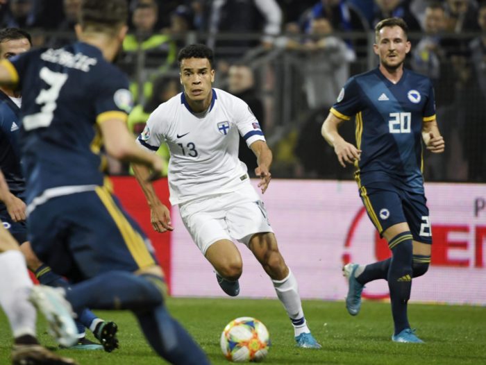 A Finnish player dribbles the football between several opponents.