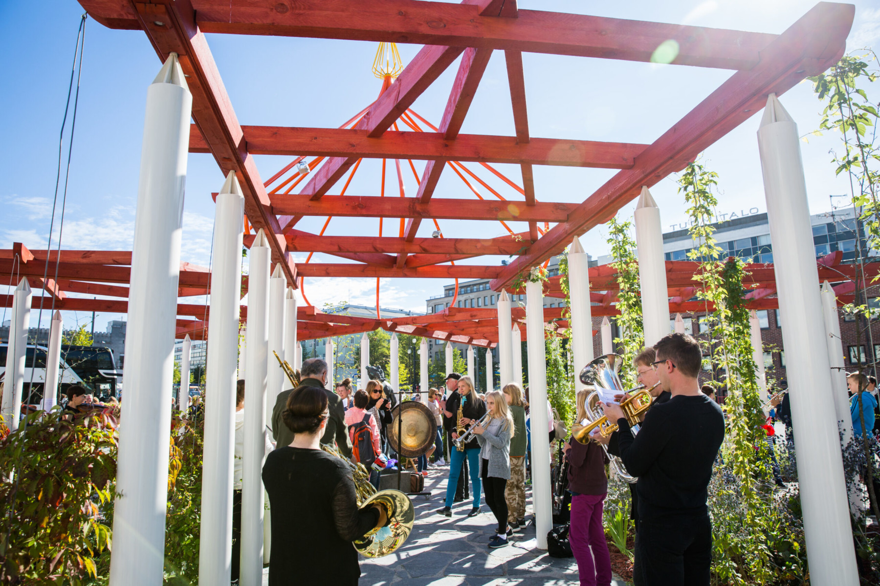 Band members play wind instruments along an outdoor walkway.