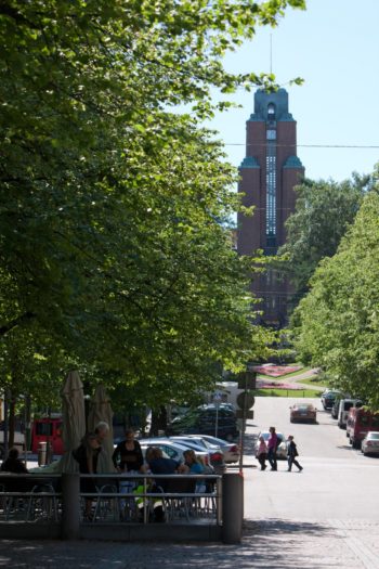 A tower is visible at the end of a tree-lined street.