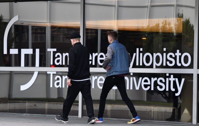 Duas pessoas passam por uma placa que diz Universidade de Tampere.