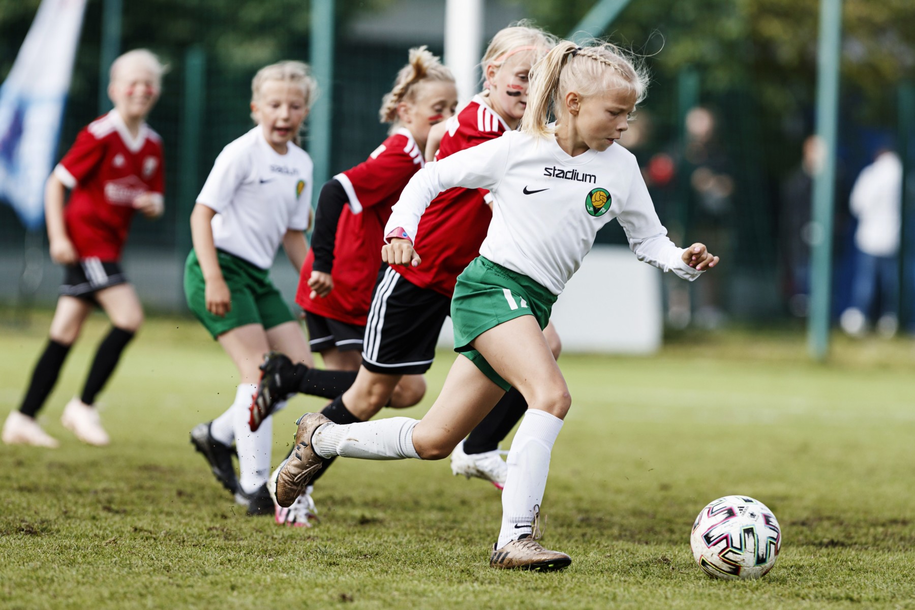 Une jeune fille qui s’est échappée avec un ballon de foot devant plusieurs autres filles s’apprête à dribbler.