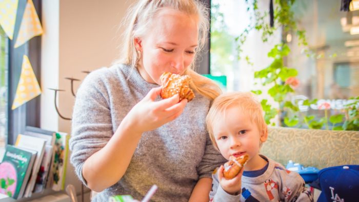 A woman and a small child are eating buns at a café.
