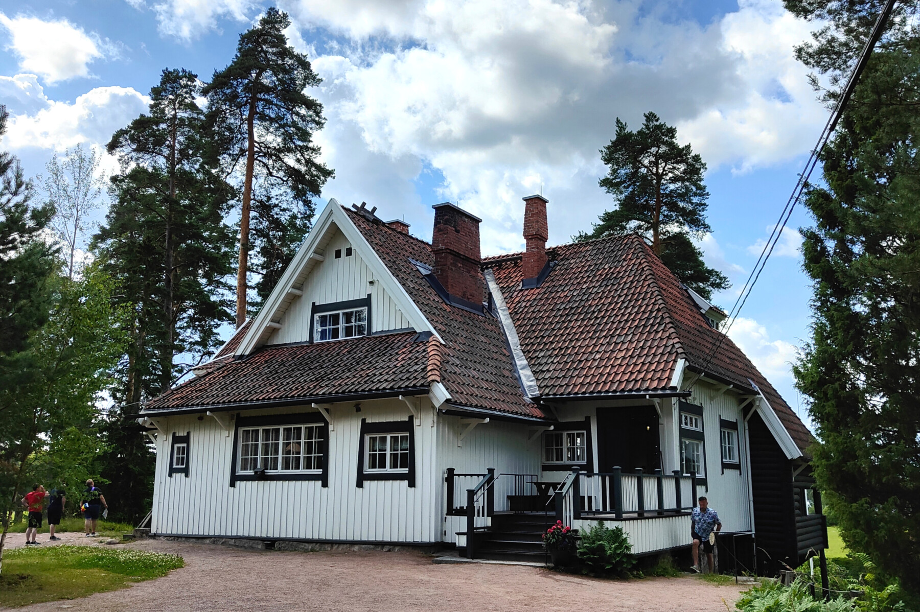 A stately white house stands among tall trees.