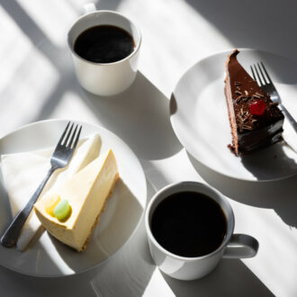 Two cups of coffee and two plates with pieces of cake are on a table.