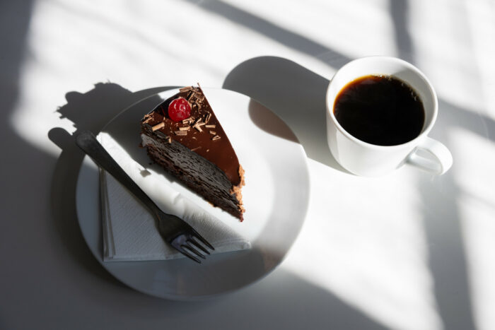 A cup of coffee and a piece of chocolate cake are arranged on a table.